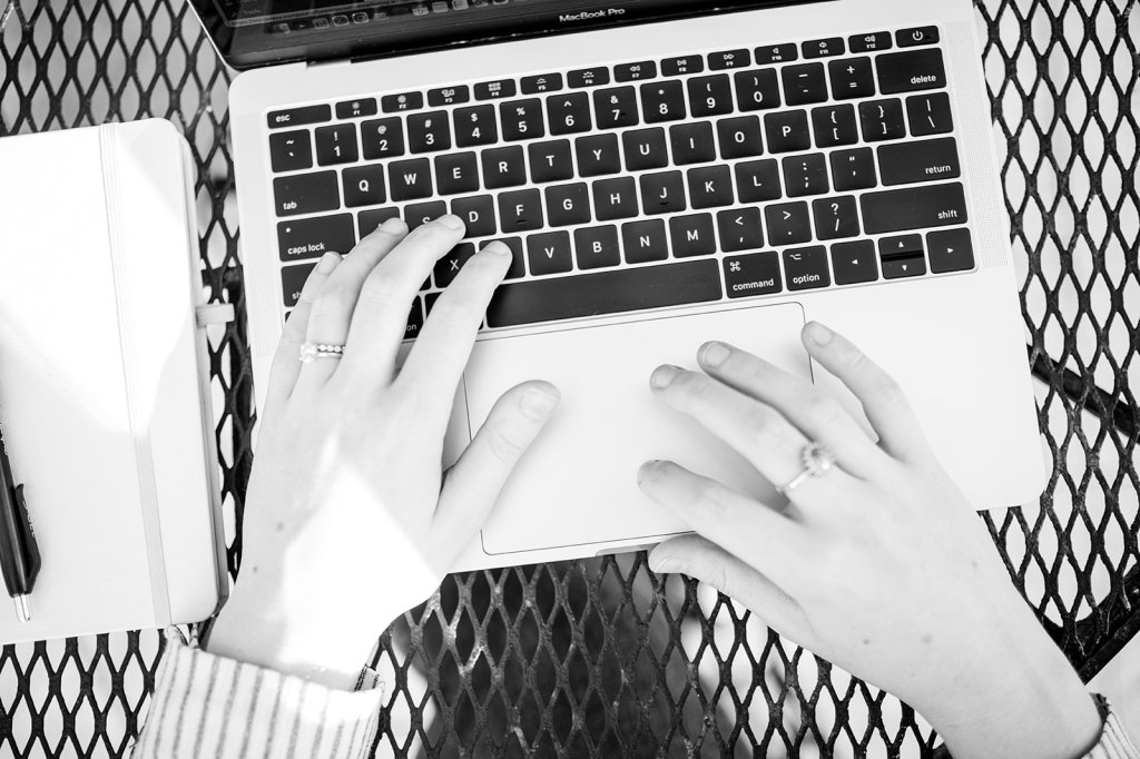 Black and white photo of a girl typing on a computer.